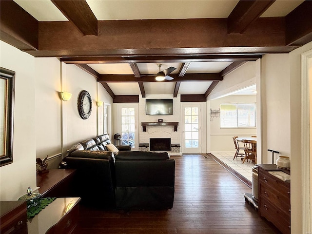 living room with ceiling fan, dark hardwood / wood-style floors, a brick fireplace, and vaulted ceiling with beams