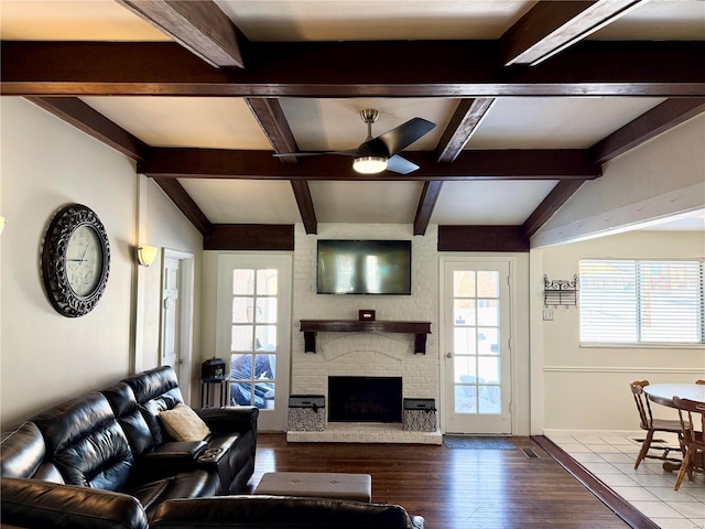 living room with lofted ceiling with beams, ceiling fan, light hardwood / wood-style floors, and a brick fireplace