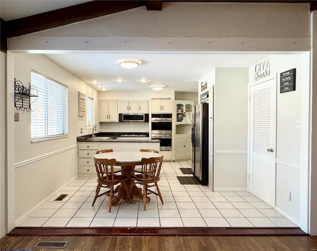 kitchen with stainless steel appliances, beam ceiling, sink, and light tile patterned floors