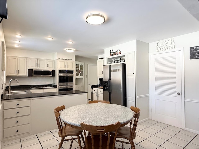 kitchen featuring tasteful backsplash, sink, light tile patterned floors, and stainless steel appliances