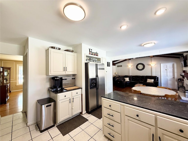 kitchen with white cabinets, dark stone counters, stainless steel fridge with ice dispenser, and light tile patterned floors