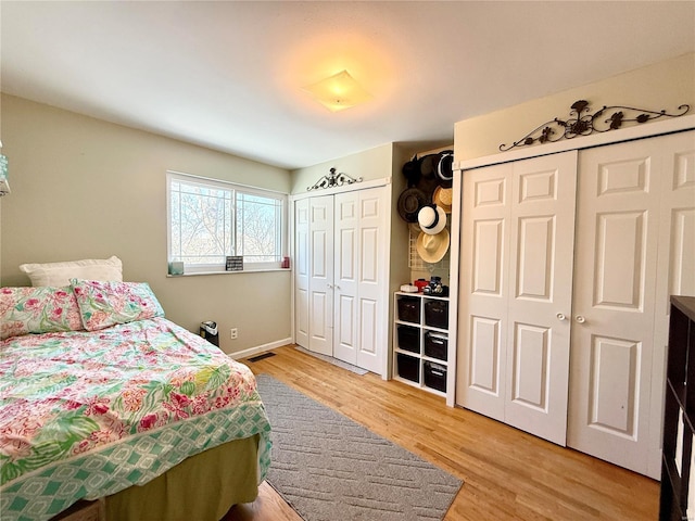 bedroom with hardwood / wood-style floors and two closets