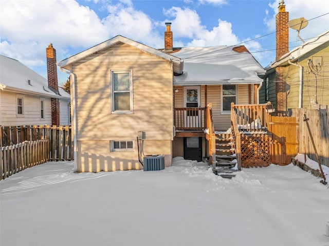 snow covered rear of property featuring cooling unit