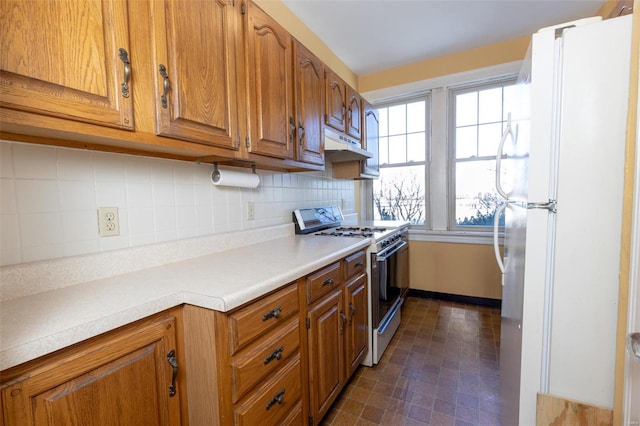 kitchen with gas range, white fridge, and tasteful backsplash