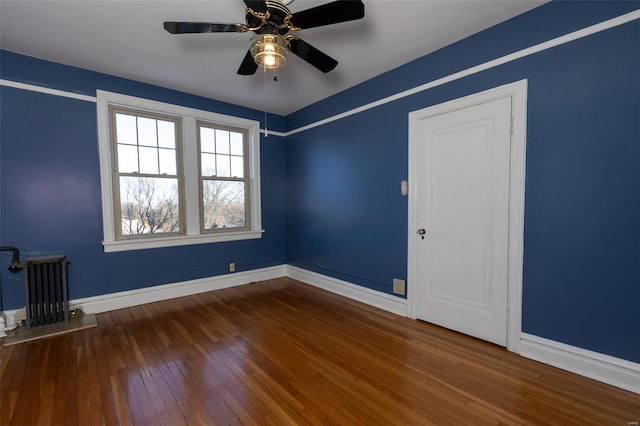 empty room with radiator heating unit, ceiling fan, and hardwood / wood-style flooring