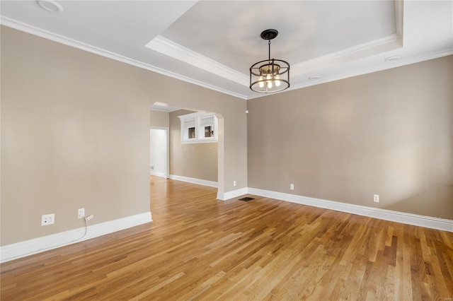 unfurnished room featuring light wood-type flooring, a tray ceiling, an inviting chandelier, and ornamental molding