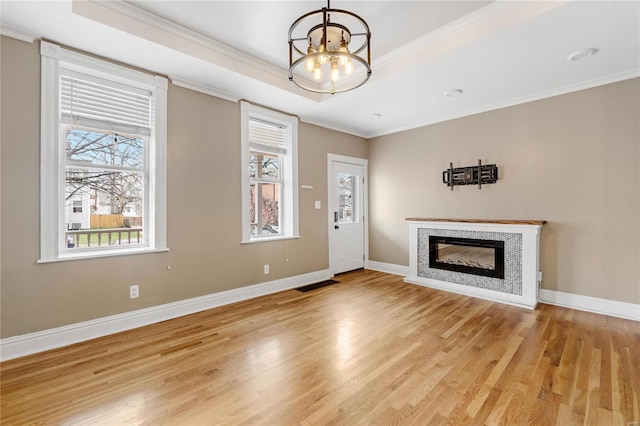 unfurnished living room with a chandelier, light hardwood / wood-style flooring, and crown molding