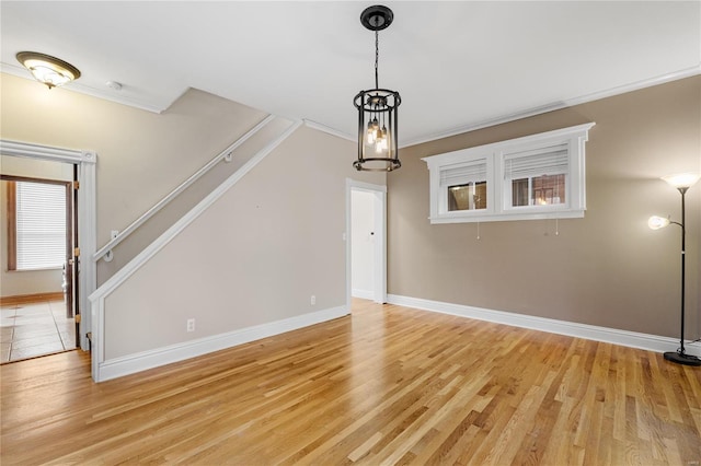 unfurnished living room with a chandelier, crown molding, and light hardwood / wood-style floors