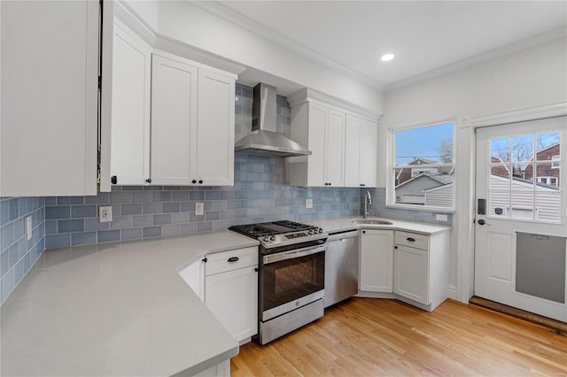 kitchen with white cabinets, wall chimney exhaust hood, and appliances with stainless steel finishes