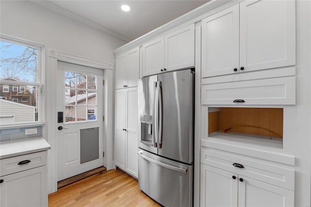 kitchen featuring stainless steel fridge, white cabinetry, crown molding, and light hardwood / wood-style flooring