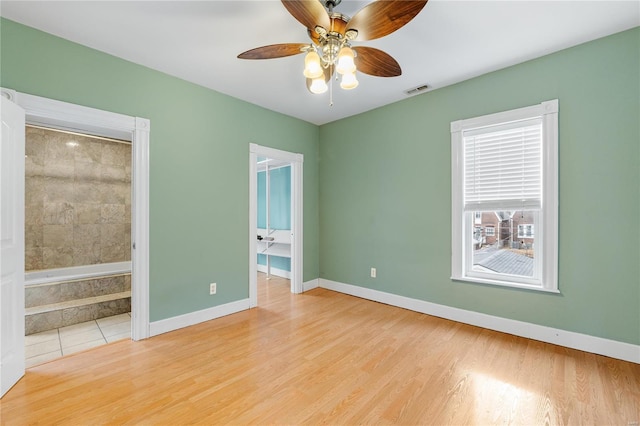 unfurnished bedroom with a closet, ensuite bath, ceiling fan, and light hardwood / wood-style flooring