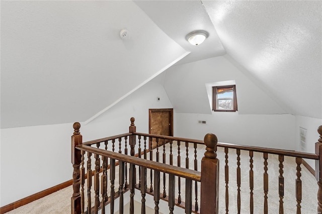 stairs featuring a textured ceiling, carpet floors, and vaulted ceiling