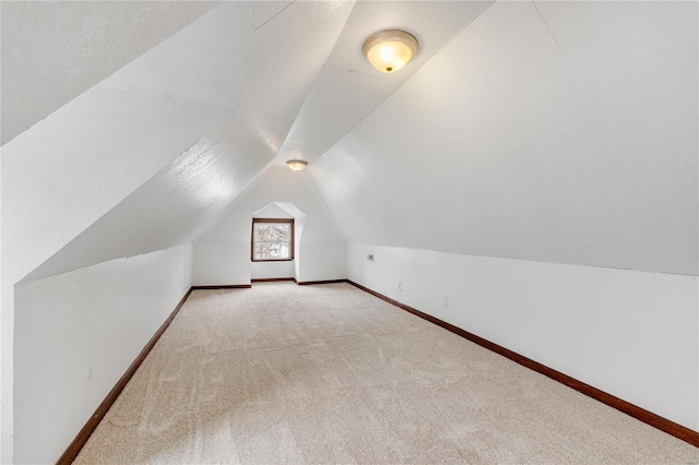 bonus room with light colored carpet and lofted ceiling