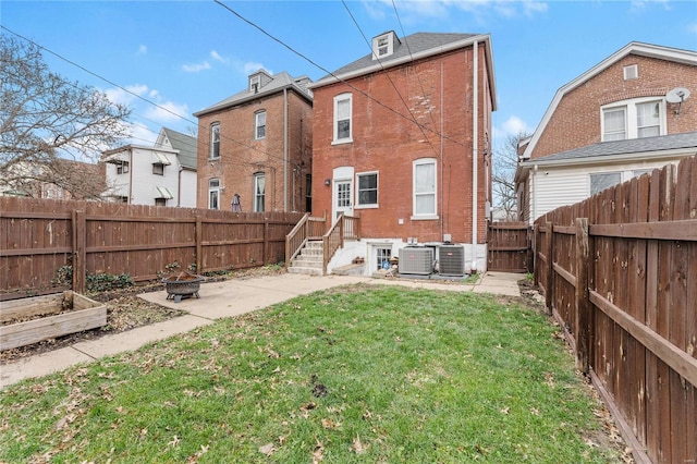 back of house with a yard, cooling unit, and an outdoor fire pit