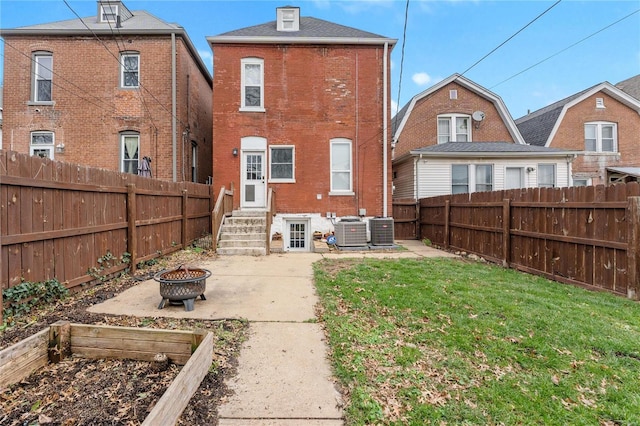 back of house featuring a fire pit, cooling unit, and a lawn