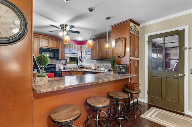 kitchen with pendant lighting, dark wood-type flooring, black appliances, sink, and kitchen peninsula