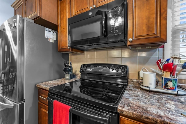 kitchen featuring dark stone counters, decorative backsplash, and black appliances