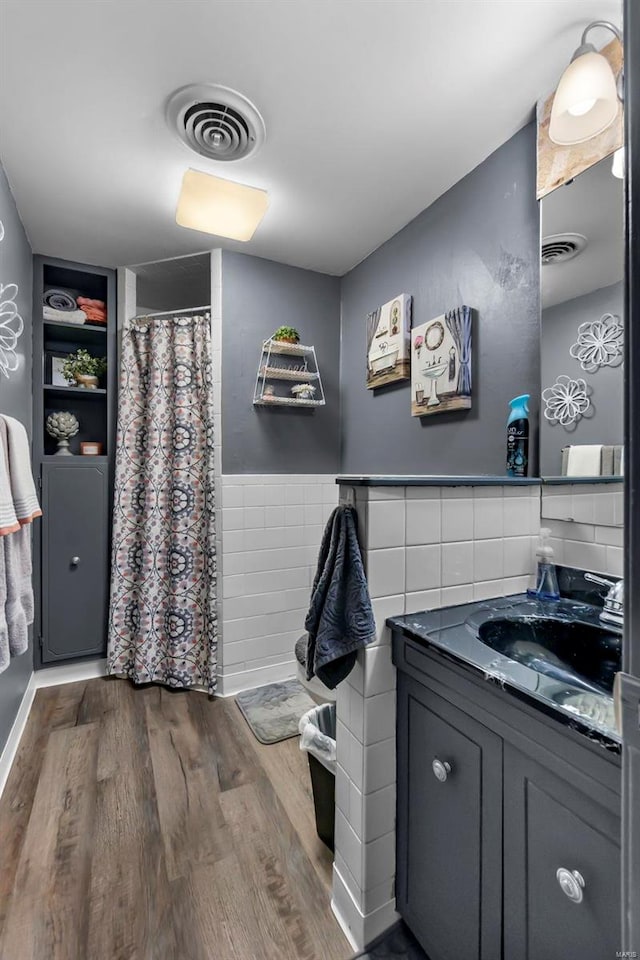 bathroom featuring vanity, hardwood / wood-style flooring, built in features, tile walls, and walk in shower