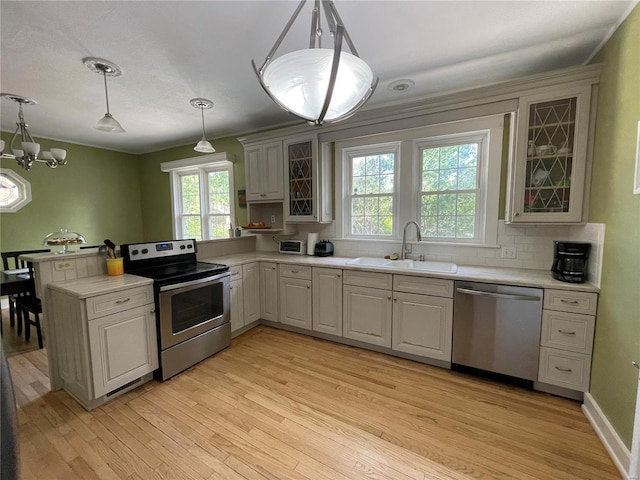 kitchen with sink, decorative light fixtures, decorative backsplash, appliances with stainless steel finishes, and a notable chandelier