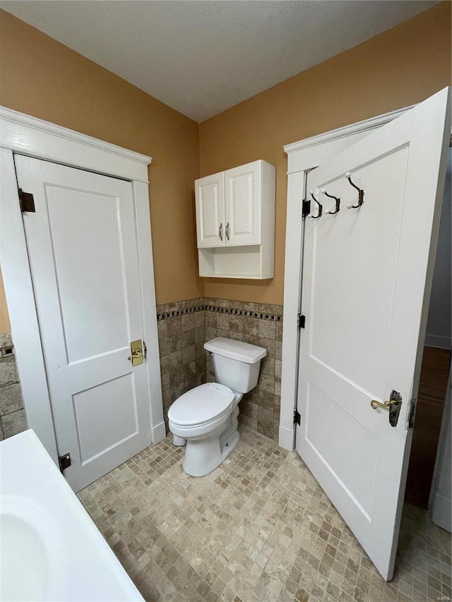 bathroom with tile walls and toilet