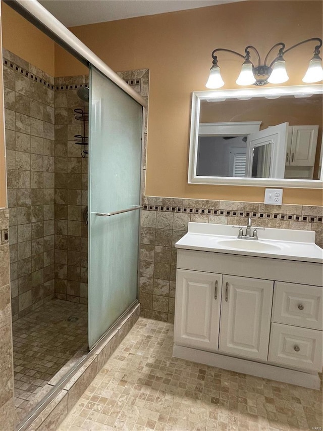 bathroom with vanity, a shower with door, and tile walls