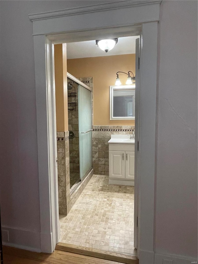 bathroom featuring vanity, an enclosed shower, and tile walls