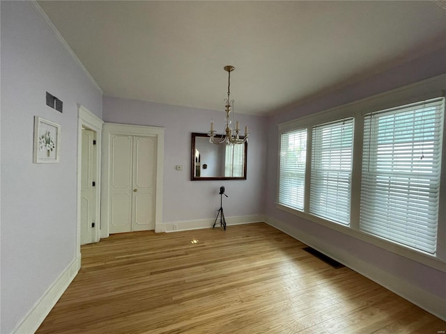 unfurnished dining area with light wood-type flooring and an inviting chandelier