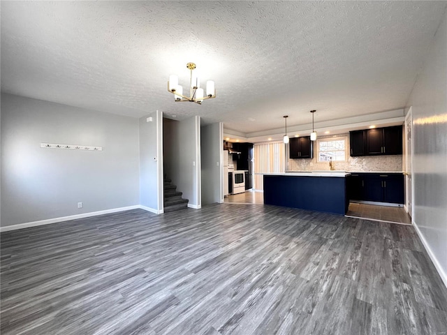 unfurnished living room with a notable chandelier, dark hardwood / wood-style floors, and a textured ceiling