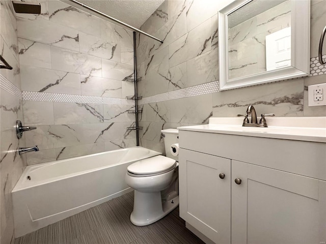 full bathroom with vanity, toilet, a textured ceiling, and tiled shower / bath