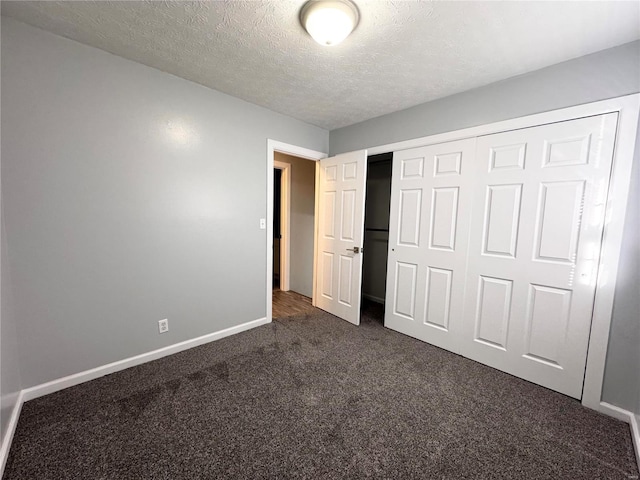 unfurnished bedroom with a closet, dark carpet, and a textured ceiling