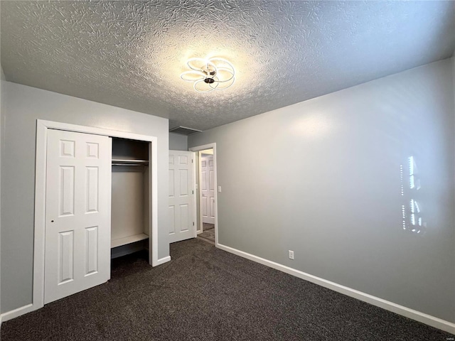 unfurnished bedroom featuring dark colored carpet, a textured ceiling, and a closet