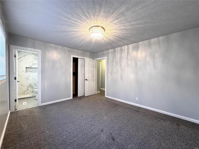 unfurnished bedroom with carpet, a textured ceiling, and ensuite bathroom