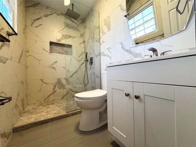 bathroom with toilet, vanity, and tiled shower