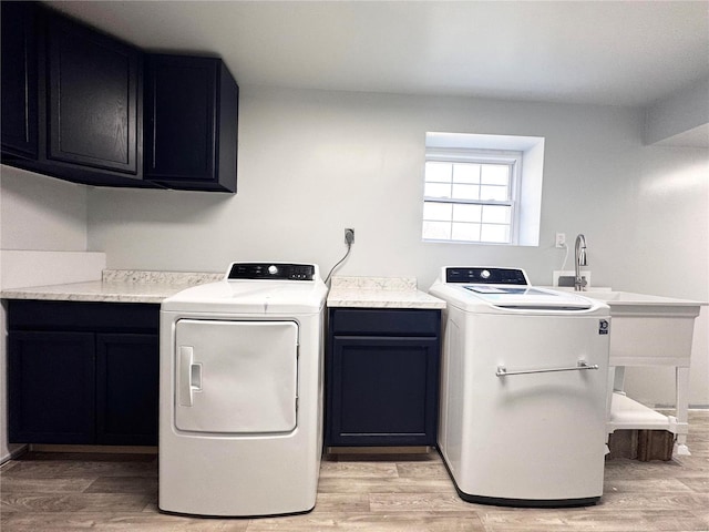 clothes washing area with separate washer and dryer, cabinets, and light wood-type flooring