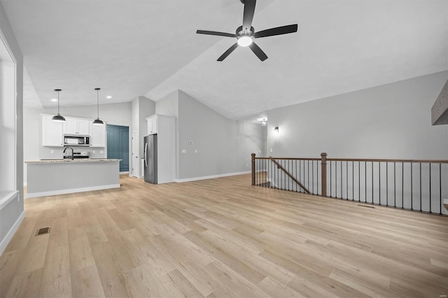 unfurnished living room featuring light hardwood / wood-style flooring, vaulted ceiling, ceiling fan, and sink