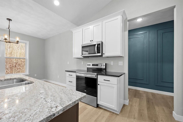 kitchen featuring pendant lighting, white cabinetry, stainless steel appliances, and vaulted ceiling