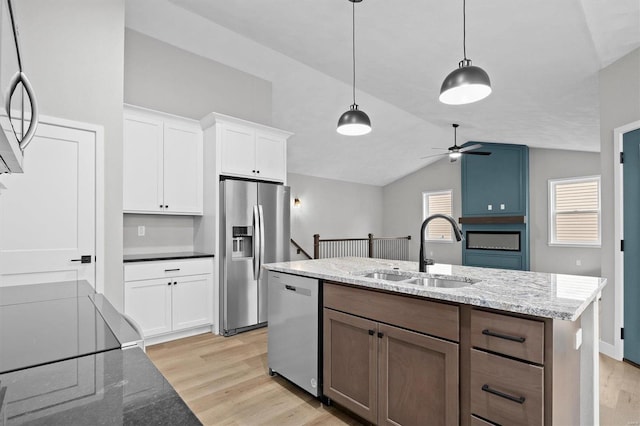 kitchen featuring appliances with stainless steel finishes, white cabinetry, lofted ceiling, and sink