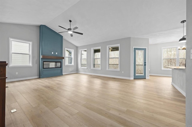 unfurnished living room with ceiling fan with notable chandelier, a large fireplace, light hardwood / wood-style flooring, and vaulted ceiling