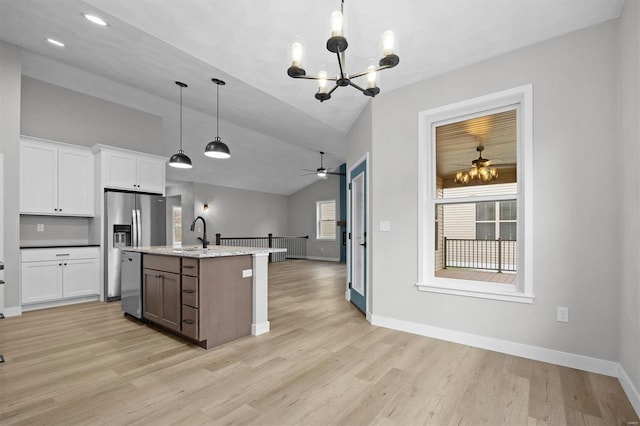 kitchen with dishwasher, lofted ceiling, a kitchen island with sink, decorative light fixtures, and white cabinetry