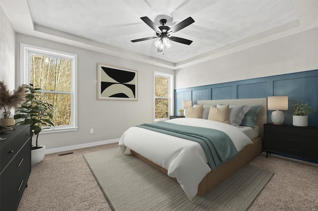 carpeted bedroom featuring a raised ceiling and ceiling fan