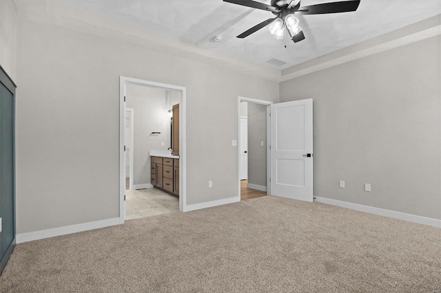 unfurnished bedroom featuring ceiling fan, light carpet, and ensuite bath