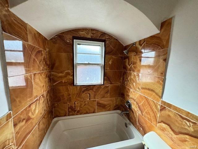 bathroom with tiled shower / bath combo and toilet