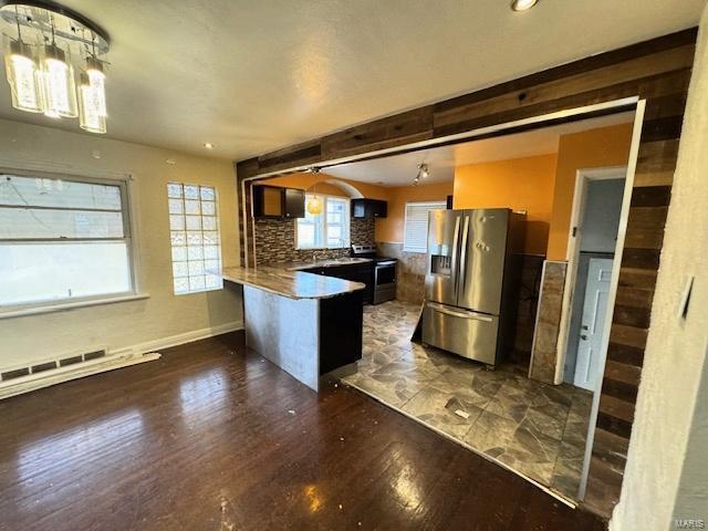 kitchen featuring kitchen peninsula, appliances with stainless steel finishes, dark hardwood / wood-style flooring, tasteful backsplash, and a breakfast bar area