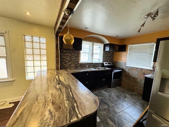 kitchen featuring electric range, sink, rail lighting, tasteful backsplash, and kitchen peninsula