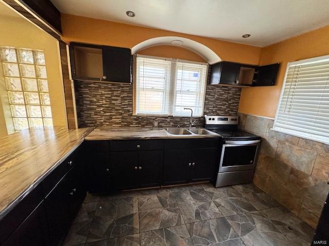 kitchen with stainless steel electric stove, backsplash, and sink