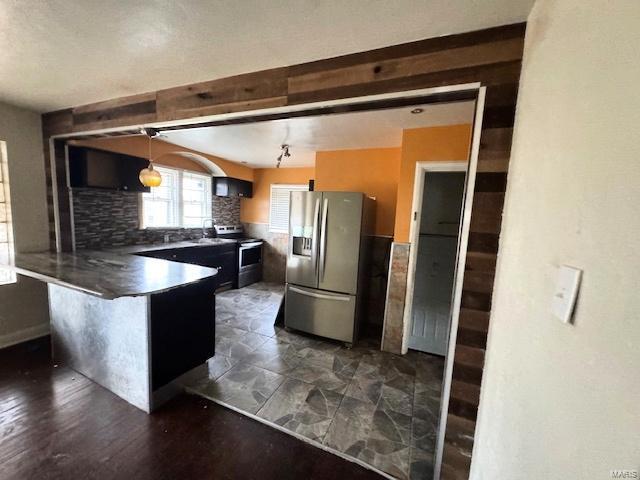 kitchen with a breakfast bar, backsplash, appliances with stainless steel finishes, decorative light fixtures, and kitchen peninsula