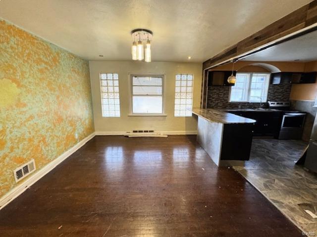 kitchen with pendant lighting, kitchen peninsula, backsplash, and a wealth of natural light