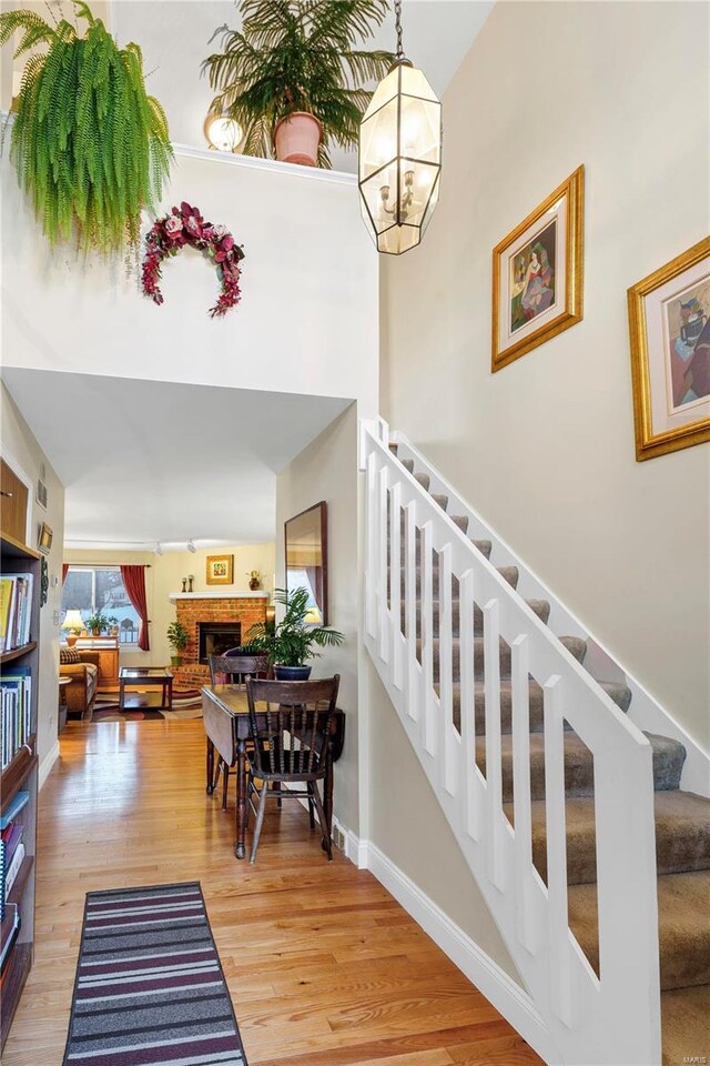 stairway with hardwood / wood-style flooring, a notable chandelier, and a fireplace