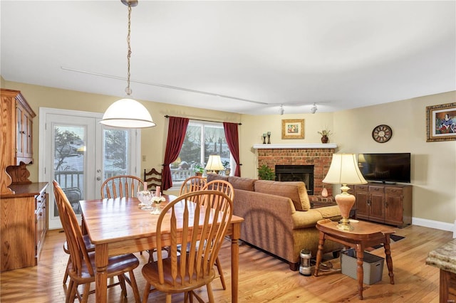 dining area with light wood-type flooring and a brick fireplace