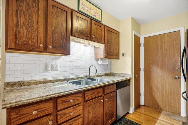 kitchen featuring backsplash, sink, light wood-type flooring, appliances with stainless steel finishes, and light stone counters